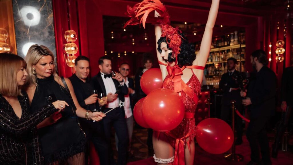A pair of balloon popping burlesque showgirl dancing for a crowd at a valentine's show