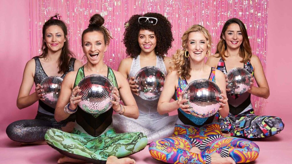 Dance Party Yoga entertainers posing with disco balls in front of a pink background as conference engagement ideas