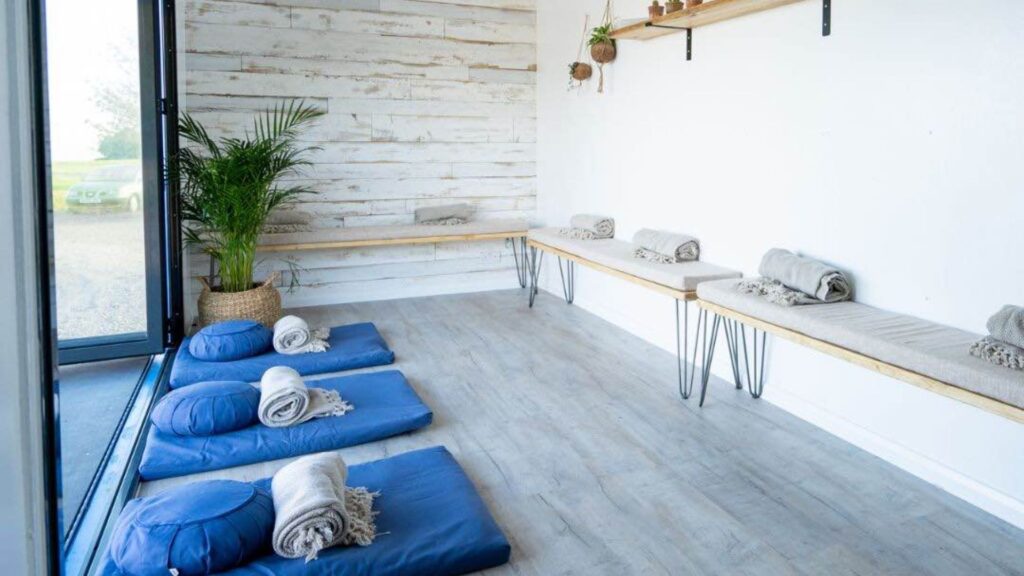 A calming mindfullness studio with blue sheets, white walls and greenery