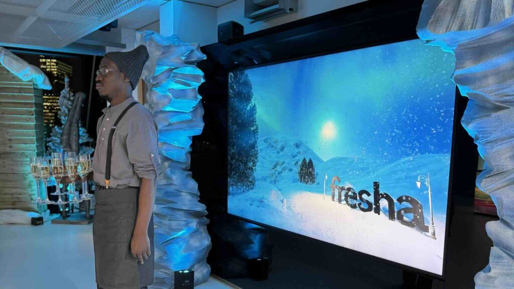 A server standing by a bespoke Fresha logo at a Corporate Christmas party