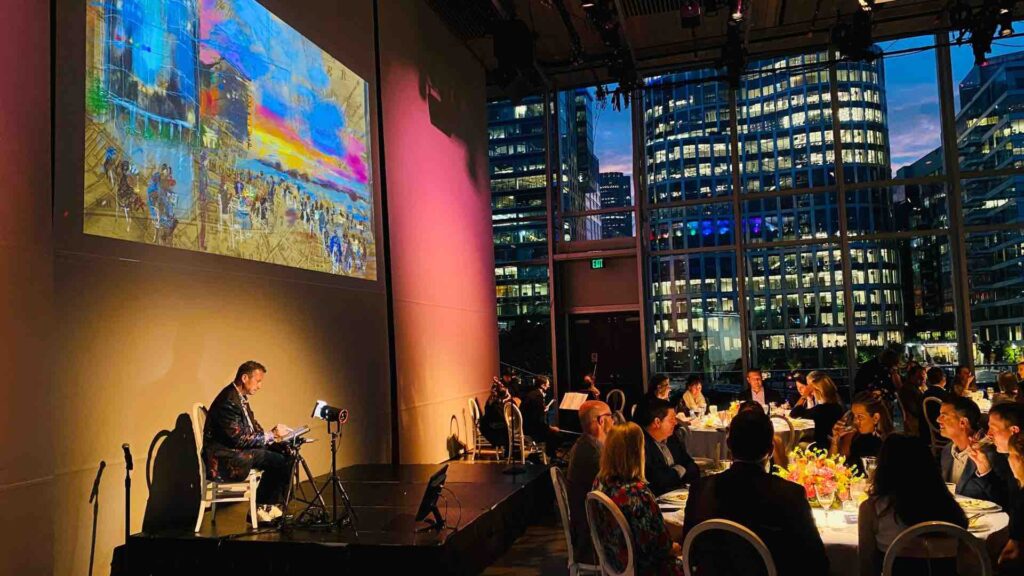 A digital artist on stage in front of a crowd at a corporate event