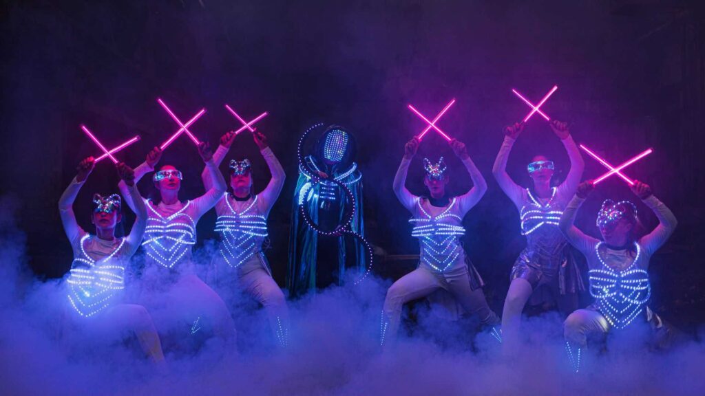 A group of LED dancers on stage with fog
