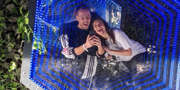 Guests posing in a sci fi themed mirror installation tunnel.