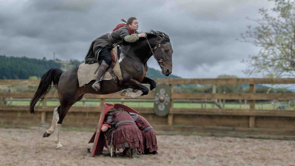 Entertainer is riding a horse over another entertainer