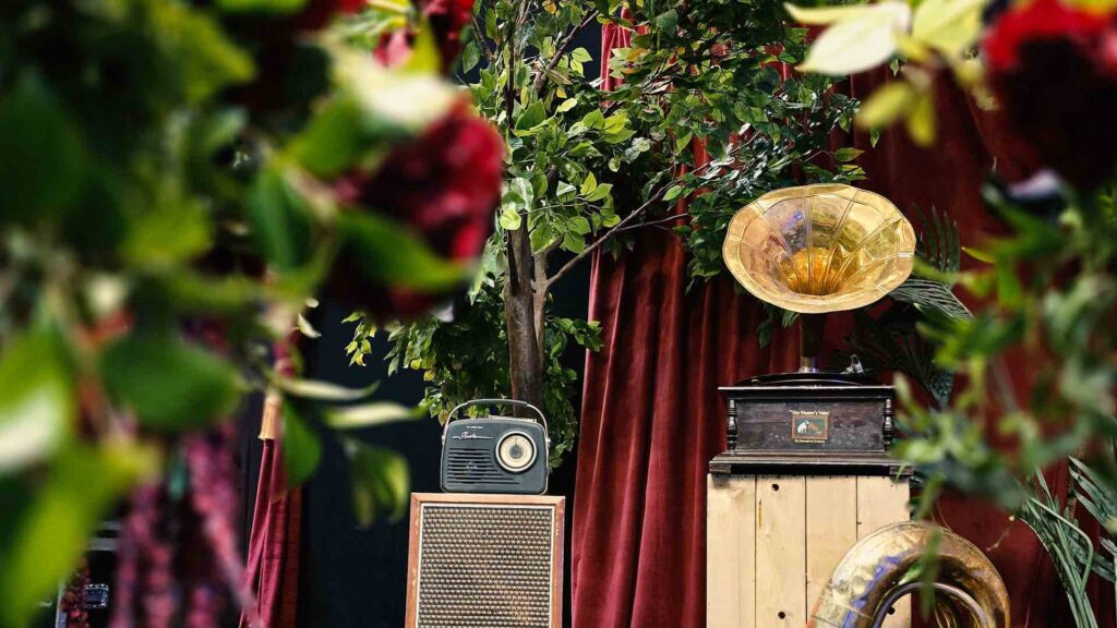 Gramophone and radio props staged at Volkswagen gala event behind flowers.