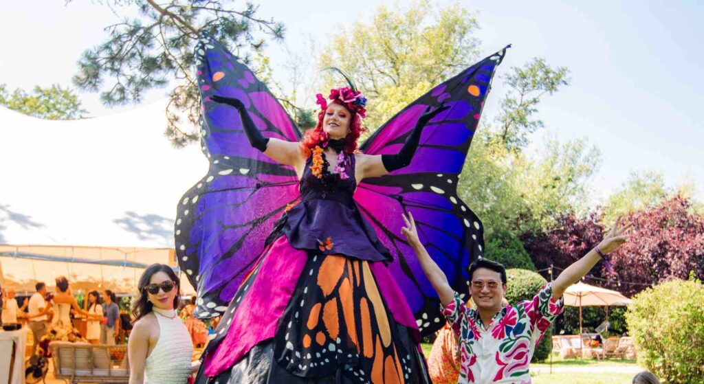 Butterfly stilt walker at festival conference posing with guests.