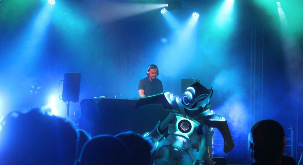 DJ playing on stage at a corporate mini-festival with LED robot.