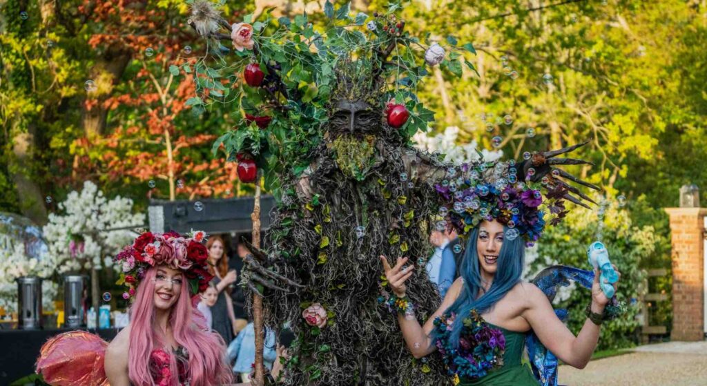 Roaming tree and fairy performers at a small festival event entertaining guests in vibrant costumes.