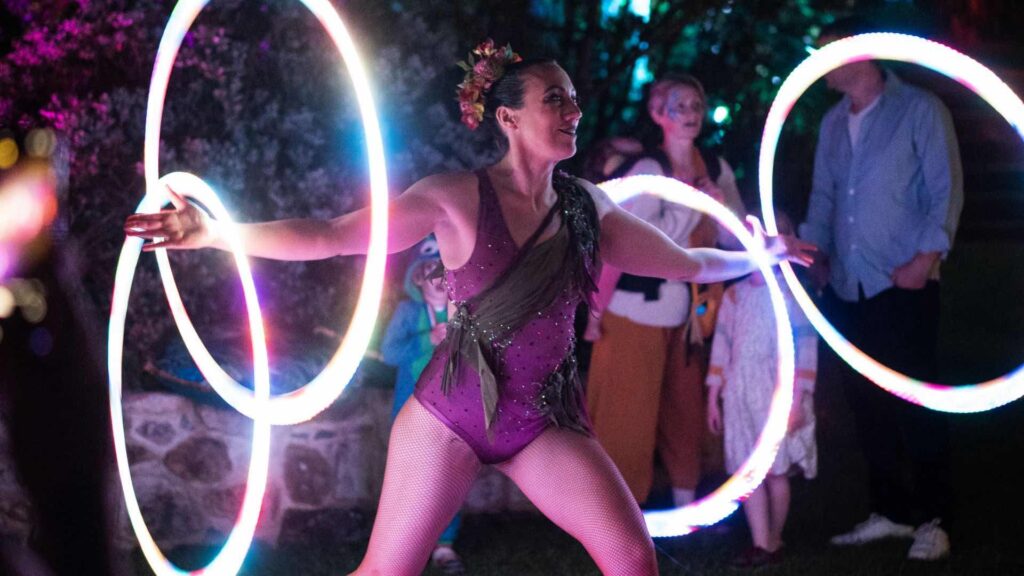 A hula hoop performer with LED hoops at a garden event