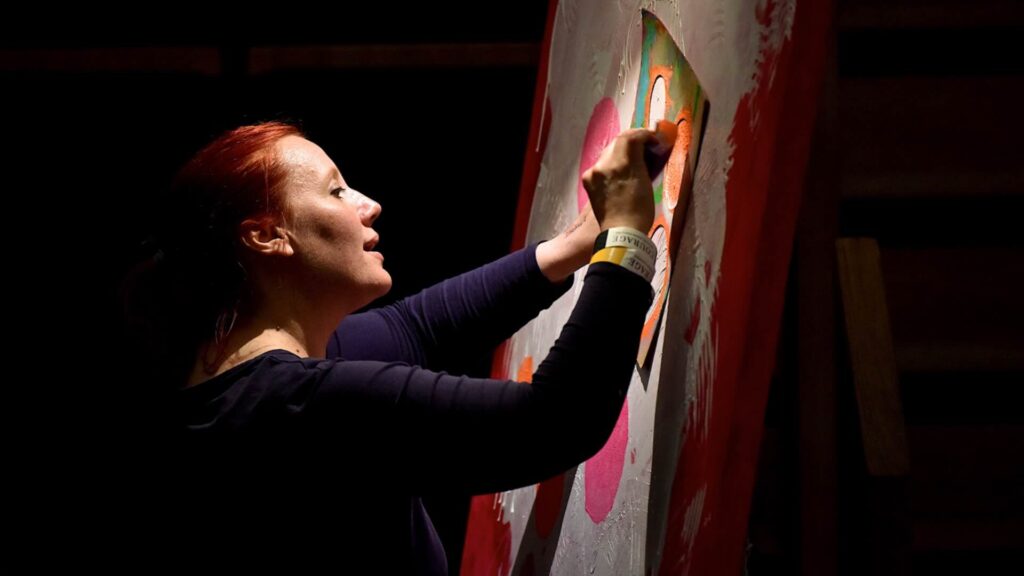 A Live Art performer painting vibrant colours with stencils