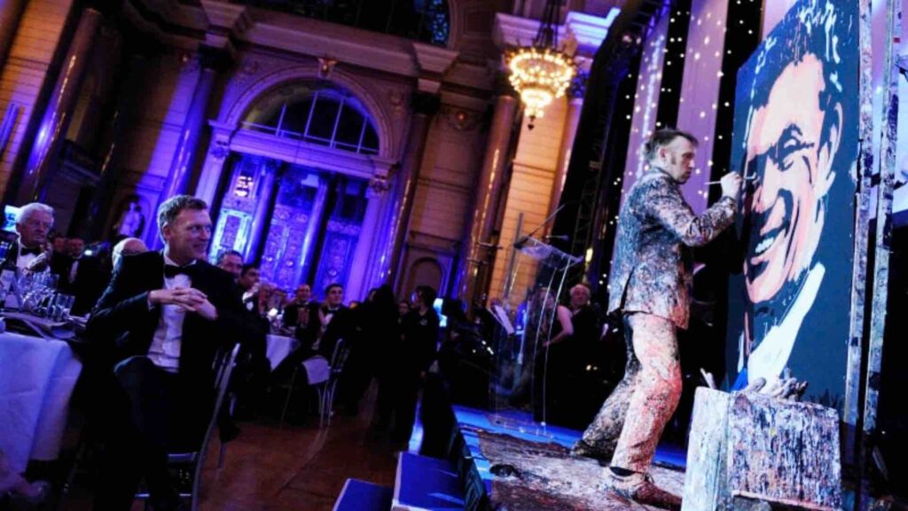 A speed painter on stage at a fancy event