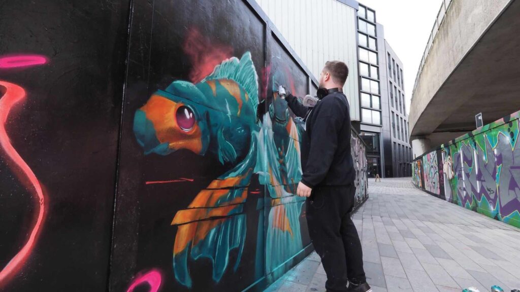 A live mural artist spray painting a wall