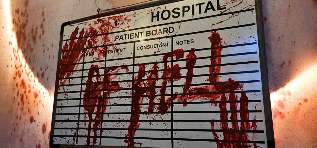 A close-up of the "HOSPITAL OF HELL" sign, drenched in blood, sets a sinister tone, immersing guests in the terrifying Asylum-themed event.