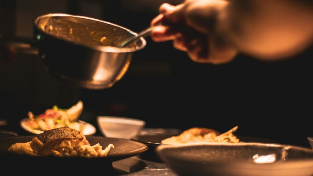 Chef serving food from live cooking station at an event.