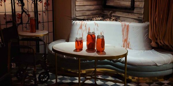 Three mason jars filled with unsettling contents rest on a table, with the interior of TABU nightclub looming in the background, adding a disturbing touch to the Asylum-themed event.