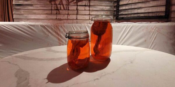 Two mason jars filled with realistic-looking organs rest ominously on a table, adding a disturbing touch to the Asylum horror scene.