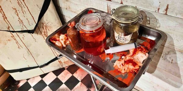Mason jars filled with severed body parts and syringes add a grotesque medical twist to the haunted hospital-themed set design.