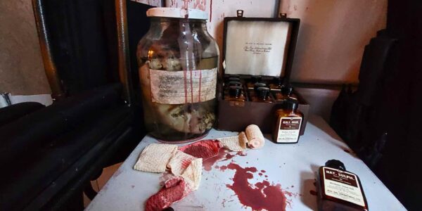 Streaked with blood, jars and medicine boxes rest on a filing cabinet, adding a disturbing touch to the Asylum-themed event decor.