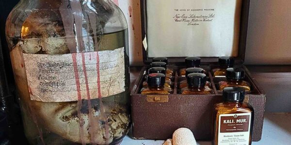 close-up reveals pills, medicine jars, and boxes scattered across a filing cabinet, their unsettling presence amplifying the horror of the Asylum theme.