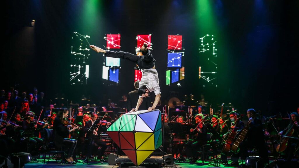 A rubik's cube performer on stage with an orchestra
