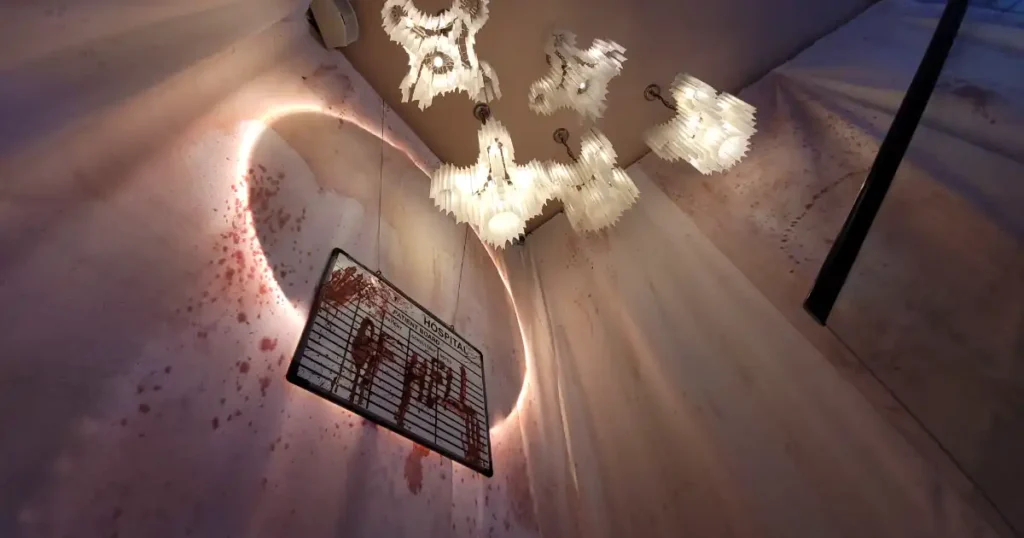 Halloween venue styling with dramatic lighting overhanging a Hospital from Hell blood smeared whiteboard on a stairwell.
