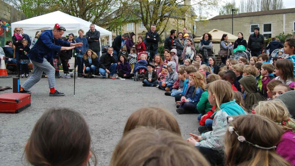 A family circus performer at an outdoor event, performing to children.