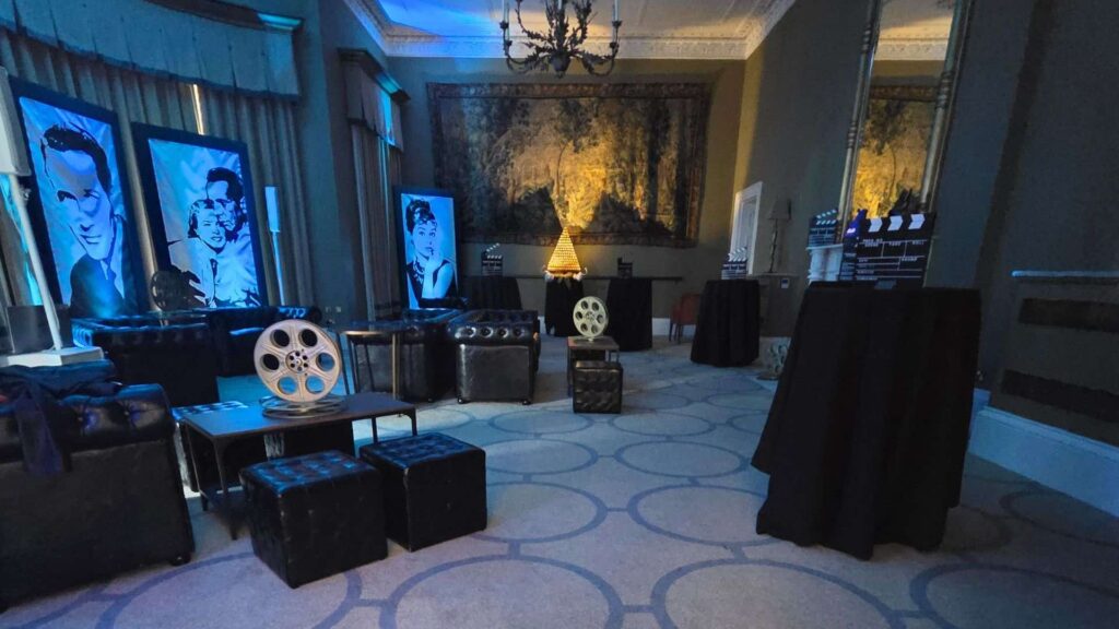 Hollywood-themed event lounge with film portraits, movie props, clapperboards and black seating