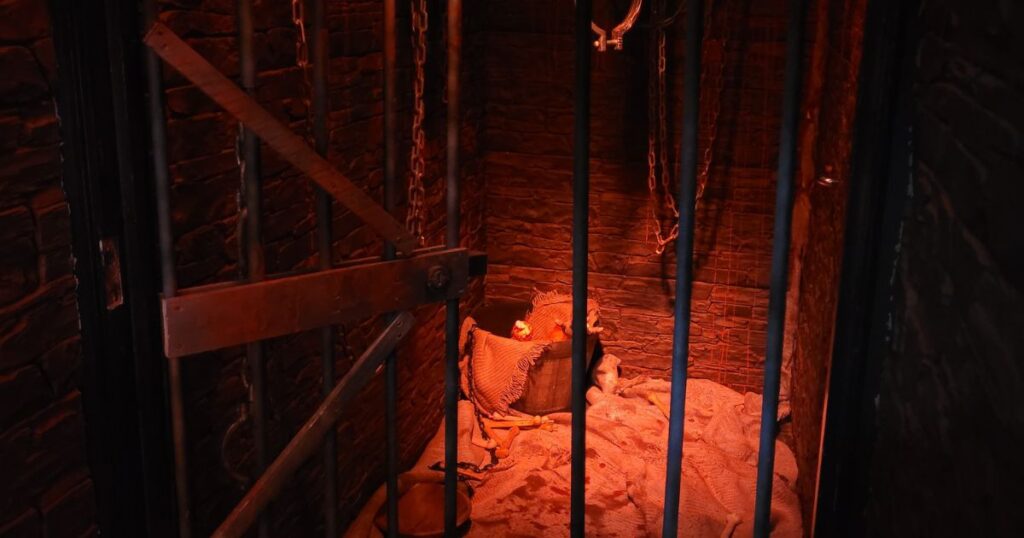 The prison cell venue theming created for REIGN nightclub with eerie red lighting, prison bars and bucket. 