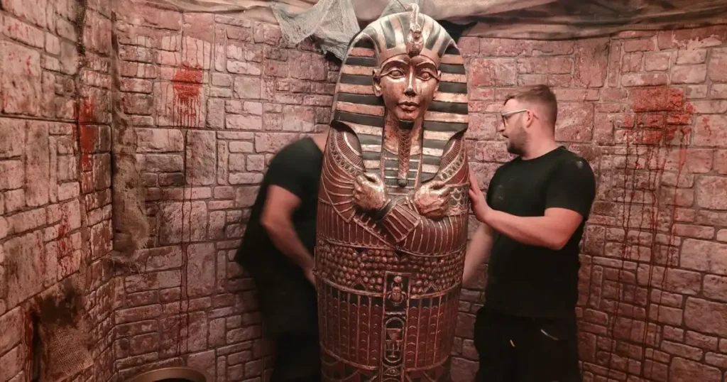 Event production team installing a dramatic Tutankhamun’s tomb-themed entrance set at a nightclub, featuring ancient Egyptian-style props and immersive decor.