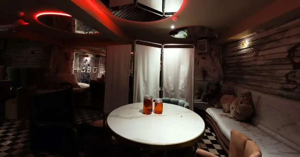 Orange mason jars sat on tables at TABU nightclub with medical folding screens in the background, used as part of a bespoke Halloween theming for their venue. 