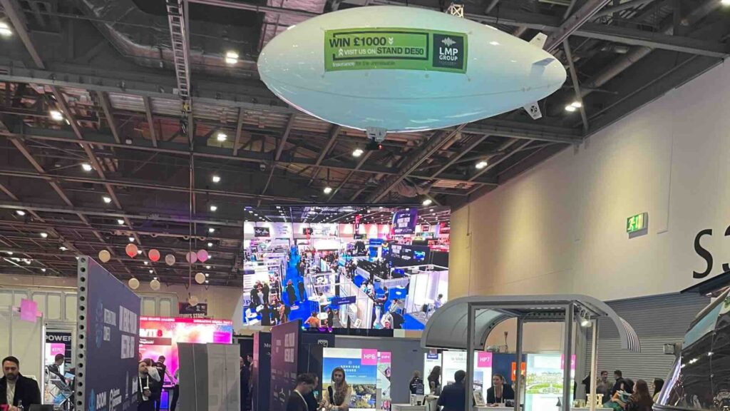 A branded airship hanging from above at an indoor exhibition.