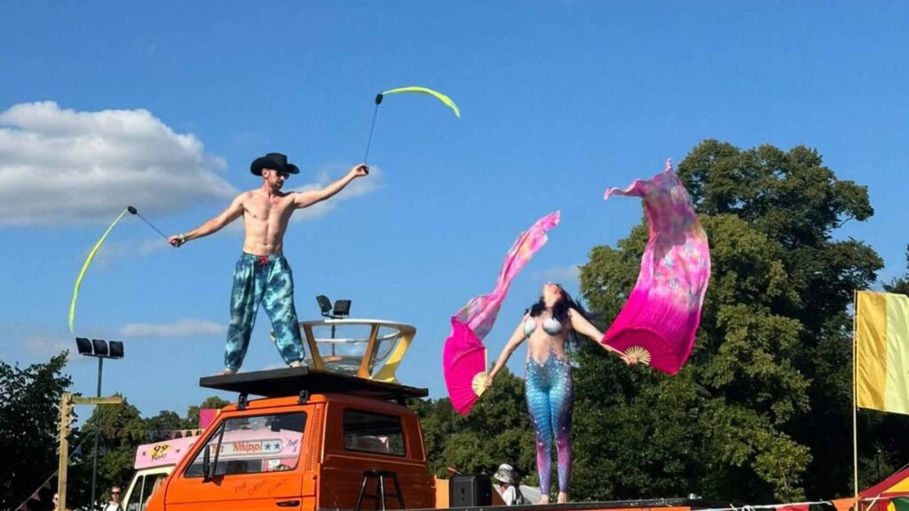 Two circus performers on top of their converted VW pickup truck.
