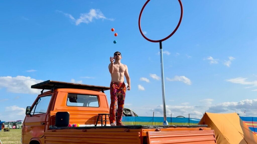 A circus performer standing on top of their VW pickup truck.