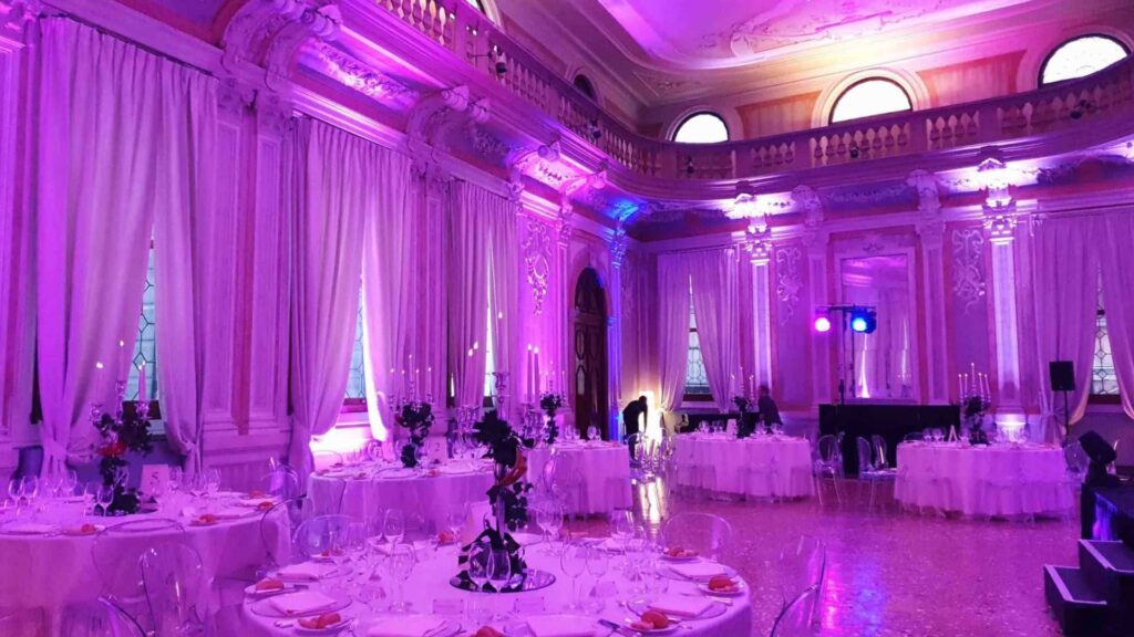 A luxury awards ceremony in Venice, with white draping, architecture and purple lighting.
