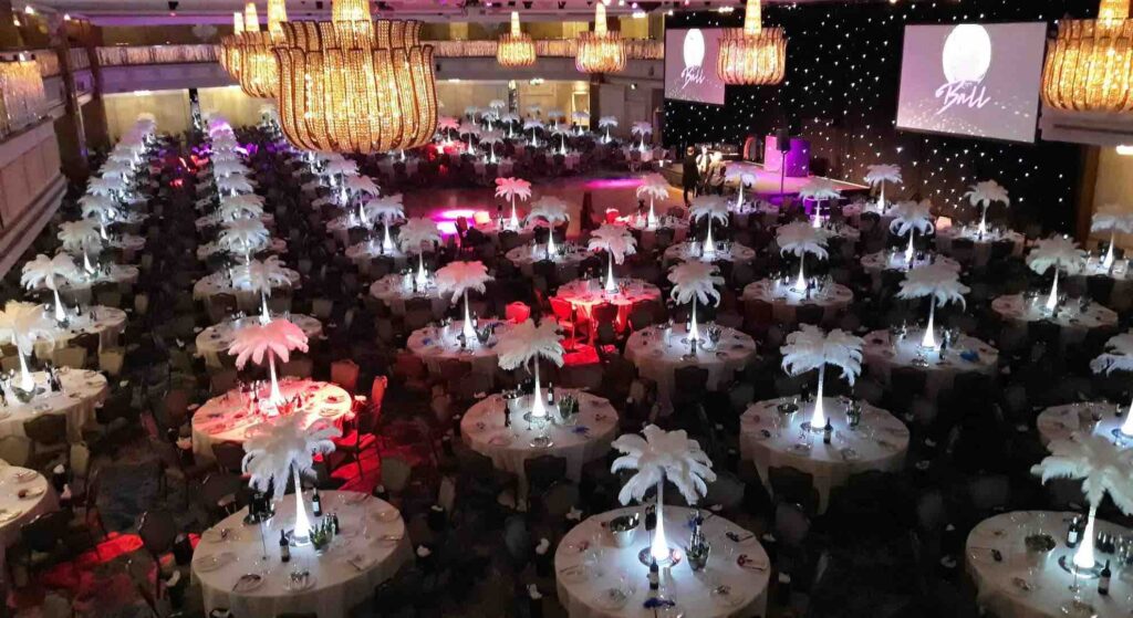 Gala event planned and produced by Julia Charles Event Management. Featuring chandeliers, red table linen, bespoke staging and stunning lighting. At Old Billingsgate in London.