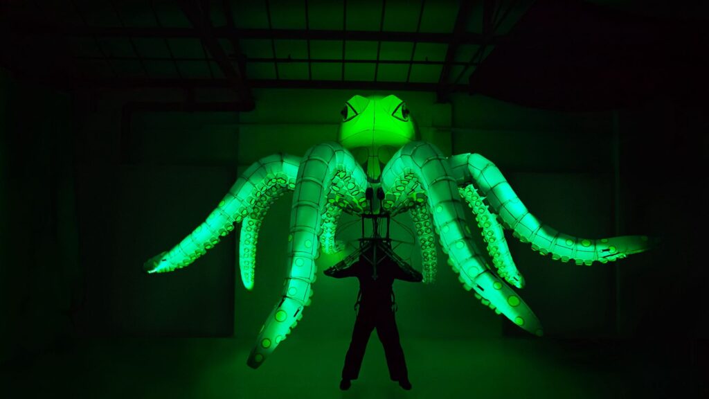 Glowing LED octopus puppet with green lighting and animatronics.