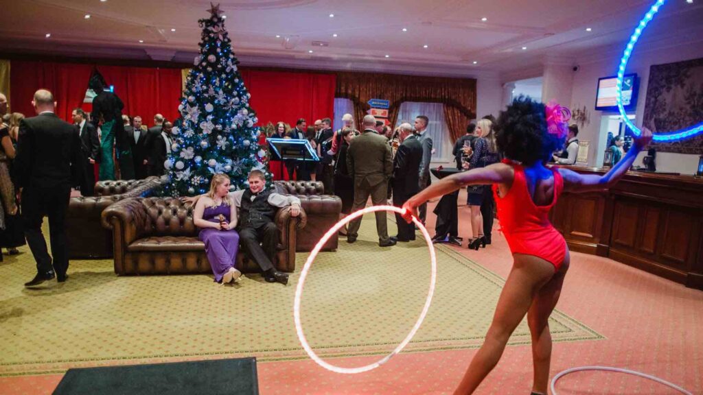 A hula hoop performer at an indoor Christmas event venue.