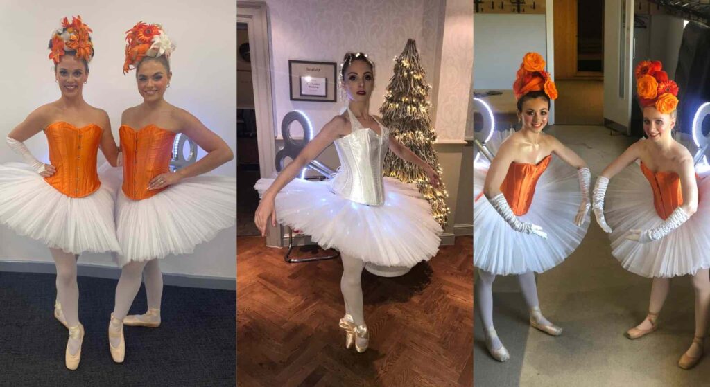LED clockwork ballerinas with orange and white corsets posing at Christmas event.