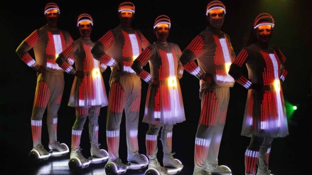 LED performers in red santa pixel poi costumes standing together.