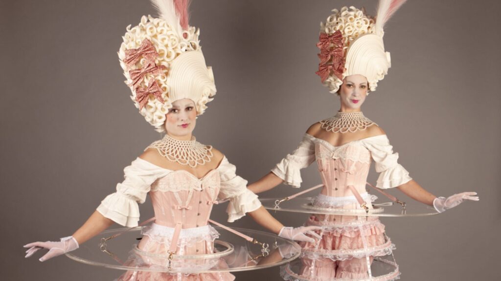 Two luxury walkabout tables in stunning white dresses and large white wigs.