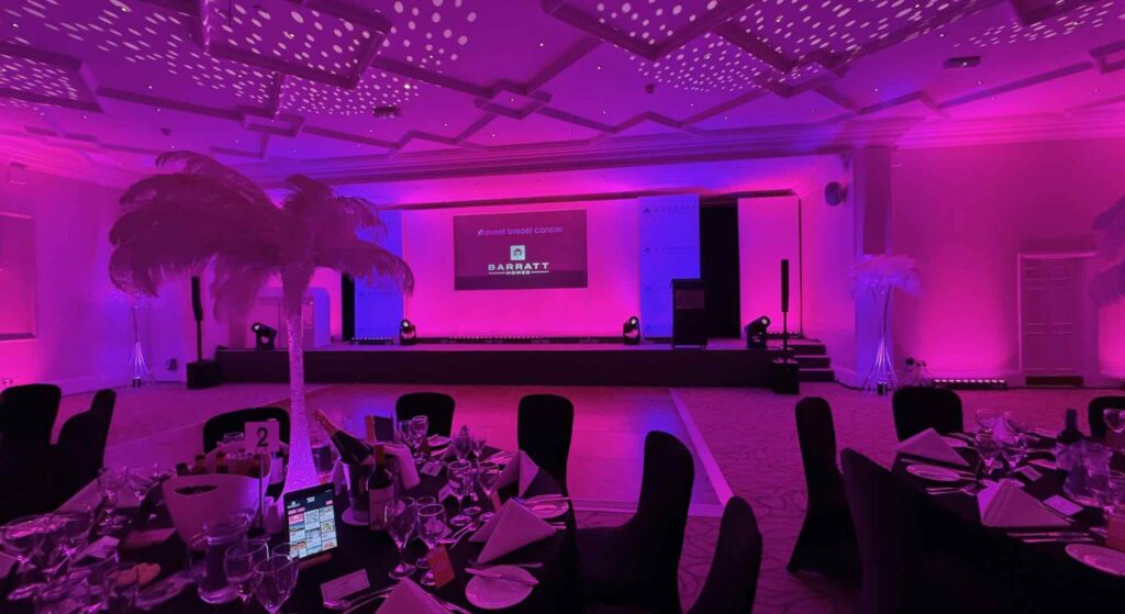 Barratt homes gala dinner event with staging, feather centrepieces, dark linen and pink lighting.
