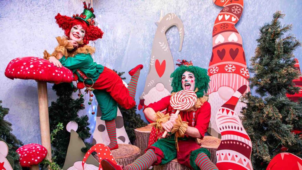 Christmas Elf performers in bright, festive costumes posing at a shopping centre Christmas activation.