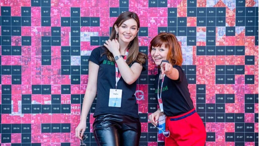 Attendees placing printed photo stickers onto a physical mosaic wall at a live event.