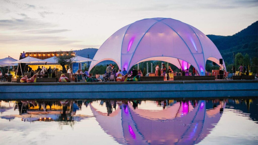 Customised premium dome hire at a festival by the waterside with purple branding.