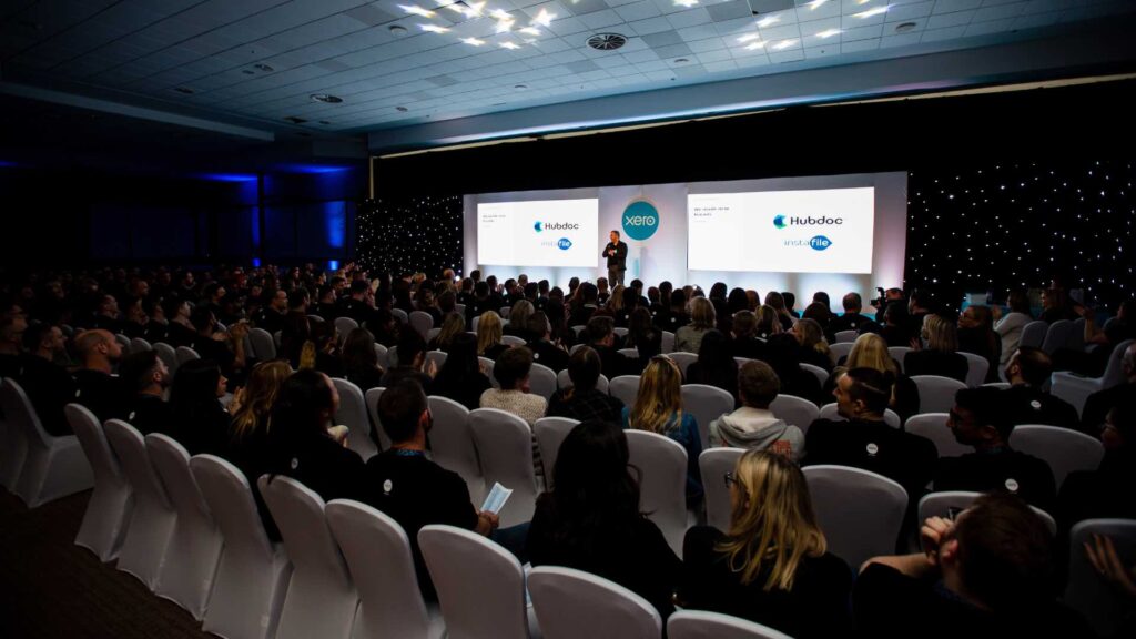 Speaker live on stage at the XERO conference hosted at Milton Keynes MK Dons venue.