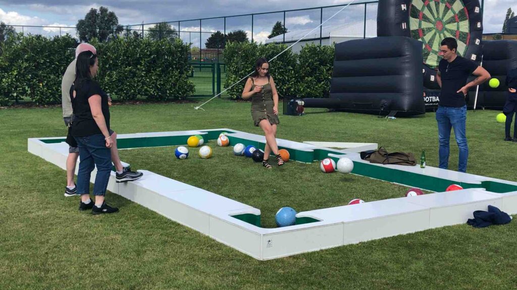 Adults playing giant football pool at an outdoor summer event.
