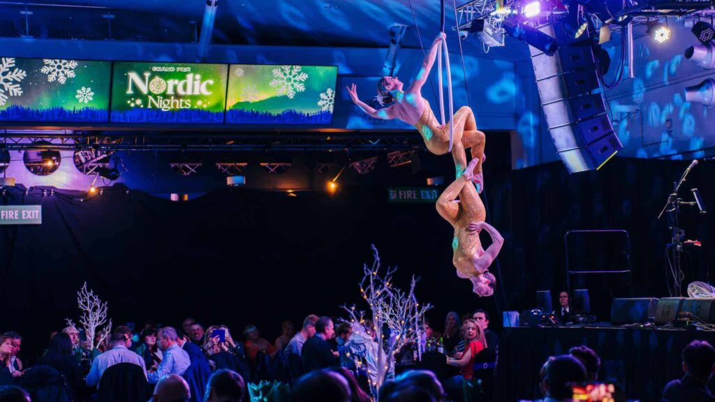 An aerial duo act hanging from a hoop and using one another to balance.