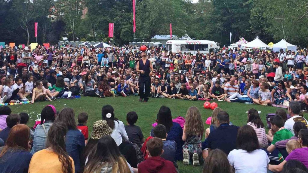 A football skills performer surrounded by a large crowd at an outdoor event.