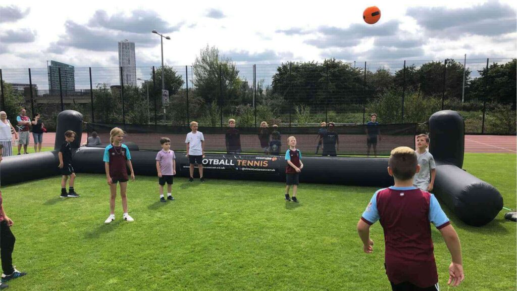 An inflatable football tennis activation at an outdoor event for all ages.