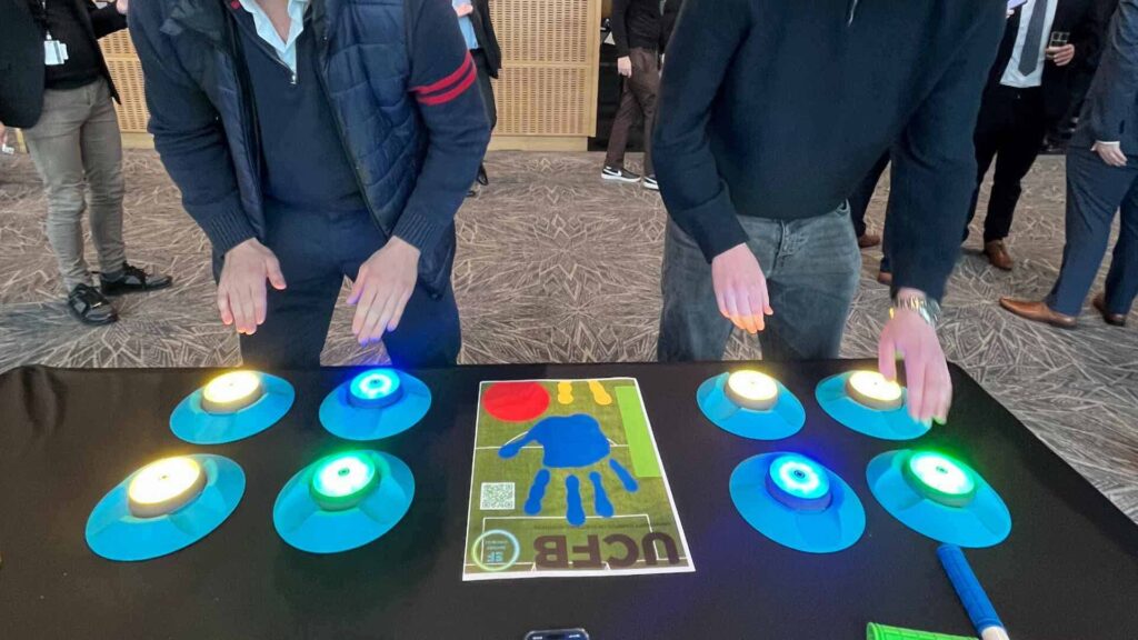 Two competitors playing against each other at an event, tapping LED buttons with their hands as quickly as possible.